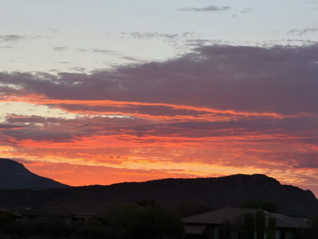 Sunrise over the mountains near Anthem, AZ, with a band of red and orange clouds above dark silhouetted peaks