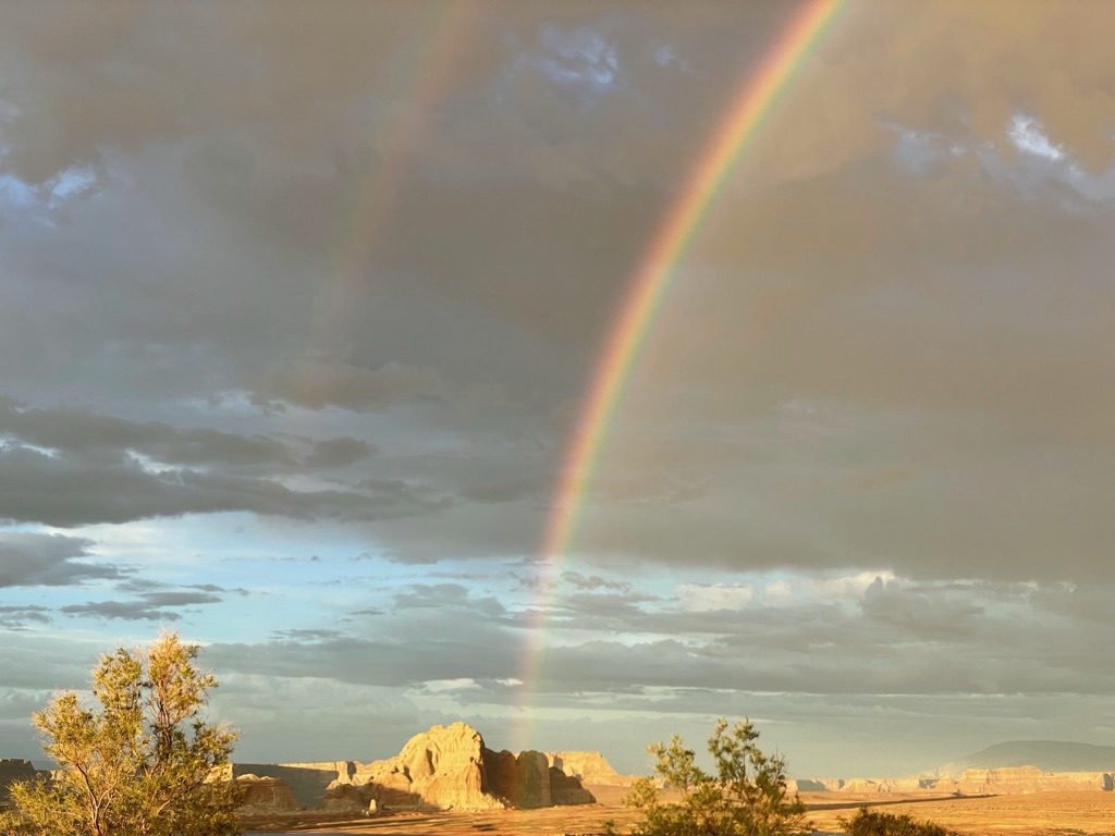 Double rainbow over a desert canyon landscape at sunset.